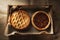 High angle view of an apple pie and pecan pie in a wood box lined with parchment paper. Horizontal format on a burlap table cloth