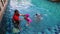 High angle view of asian family having fun in swimming pool outdoors. Active kids. Footage may contain noise due to low light