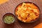 High angle view of basil pesto sauce with nachos corn chips in colorful plates on a bamboo table mat