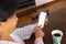 High angle view of biracial mature woman with coffee on wooden table using mobile phone at home