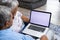 High angle view of biracial senior couple using laptop while relaxing on sofa in living room