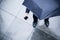 High angle view of businessman holding an umbrella and looking at his phone in the rain