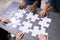 High Angle View Of Businesspeople Solving Jigsaw Puzzle