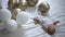 High angle view carefree newborn baby lying on white soft comfortable bed with balloons around. Wide shot happy