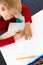 High angle view of caucasian elementary schoolboy writing on book while sitting at desk in school