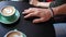 High angle view coffee cups on table with male hand making effort to touch female palm. Dissatisfied unrecognizable