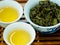 High angle view of cups of green oolong tea and tea leaves on a wooden tray