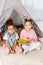 high angle view of cute multiethnic kids sitting on carpet with book and smiling