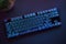 High angle view of cyan backlighted gaming computer keyboard laying on desk