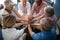 High angle view of female doctor amidst seniors stacking hands