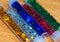 High angle view of five long tubes with caps filled with colorful star sprinkles on a wooden table