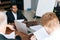 High-angle view of focused multi ethnic business men checking agreement document before signing it sittng at desk in