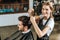 High angle view of hairstylist smiling at camera while cutting hair to handsome client