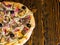 High angle view of half of tasty pizza with ham, mushrooms, olives