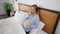 High angle view of happy smiling pregnant woman lying in bed listening to music in headphones stroking belly in slow