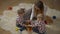 High angle view of happy young millennial mother and twin daughters playing with ukulele in family room. Wide shot of