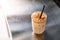 High angle view of an iced coffee latte with straw on a steel counter top in coffee house