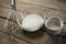 High angle view of milk and flour in bowls by wire whisk