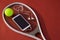 High angle view of mobile phone with in-ear headphones and ball on tennis racket