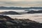 High angle view of mountaintops surrounded by clouds