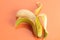 High angle view of a peeled banana on a peach background