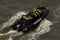 High-angle view of people with green life jackets in the RIB speedboat on the waves