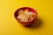 High angle view of potato chips in red bowl on yellow background