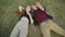 High angle view of relaxed Caucasian couple of teenagers lying on green grass talking and pointing up. Portrait of