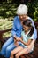 High angle view of smiling grandmother looking at granddaughter using mobile phone on wooden bench