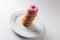 High angle view of stack of fresh pink donuts in plate against white background