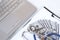 High angle view of stethoscope and dollar banknotes on clipboard with laptop keyboard on white marble tabletop, medical expense