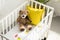 high angle view of teddy bear, other toys and yellow pillow in baby crib