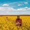 High angle view of two farm workers examining crops in blooming rapeseed field on bright sunny spring day