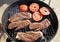 High angle view of two succulent steaks cooking on a barbecue over the hot coals on a green lawn outdoors