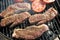 High angle view of two succulent steaks cooking on a barbecue over the hot coals on a green lawn outdoors