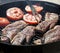 High angle view of two succulent steaks cooking on a barbecue over the hot coals on a green lawn outdoors