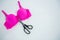 High angle view of vibrant pink bra with scissors