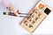 High angle view of women holding chopsticks to pick up sushi roll from set on wooden platter