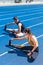 high angle view of young athletic male and female joggers sitting on running track