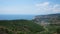 High angle wide shot of greenfield and a town with the ocean on the background