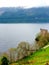 High angles view of lake side with willow trees and yellow flowers and mountains around the lake