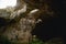 High arches of a huge stone cave with round holes at the top, a tourist road with a fence inside the cave.