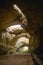 High arches of a huge stone cave with round holes at the top, a tourist road with a fence inside the cave.