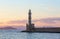 High, beautiful, ancient lighthouse made of bricks. Marvelous sunset lights the sky. Touristic resort Chania, Creete island.