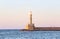 High, beautiful, ancient lighthouse made of bricks. Marvelous sunset lights the sky. Touristic resort Chania, Greece.