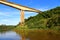 High bridge crossing a river with calm waters and vegetation on the edges.