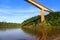 High bridge crossing a river with calm waters and vegetation on the edges.