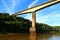 High bridge crossing a river with calm waters and vegetation on the edges.