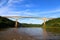 High bridge crossing a river with calm waters and vegetation on the edges.