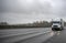 High cab big rig semi truck with dry van semi trailer driving on the wet highway road with storm raining weather at twilight